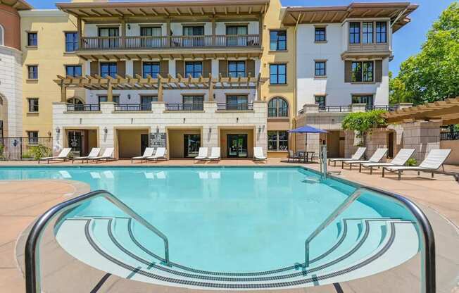A large swimming pool in front of a multi-story apartment building.