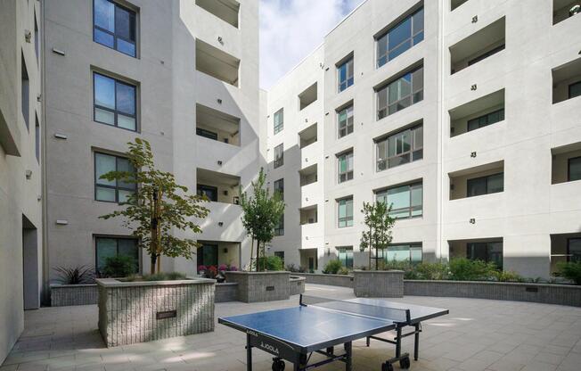 Active courtyard with a ping‑pong table, open seating, and greenery creating a welcoming spot for casual fun.