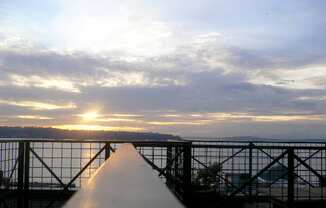 a view of the sunset over the water from the top of a bridge
