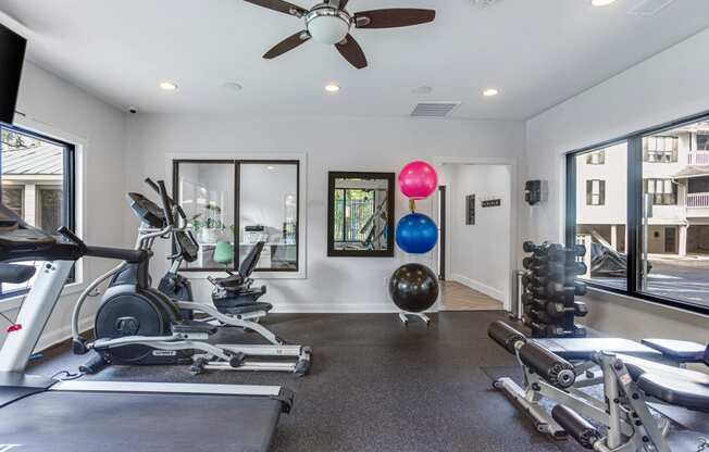 a home gym with exercise equipment and a ceiling fan
