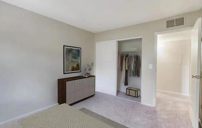 A room with a carpeted floor and a wooden cabinet with a painting on top.