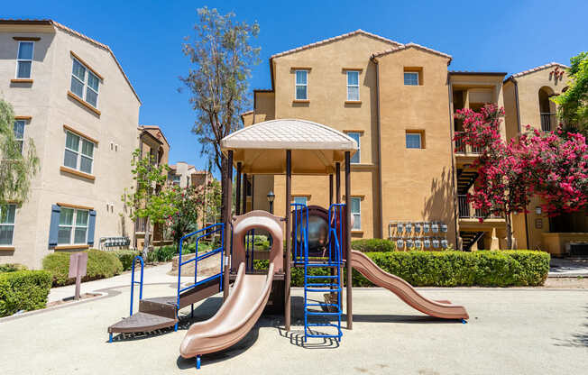 A playground with a brown slide and a blue and brown swing set.