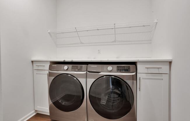 a washer and dryer in a laundry room with white cabinets