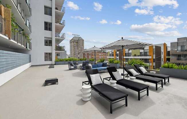 A rooftop patio with black lounge chairs and a white table.at Hollywood Ardmore, Los Angeles, CA 90028