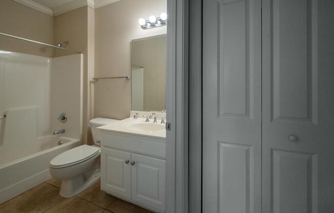 A white bathroom with a toilet, sink, and mirror.