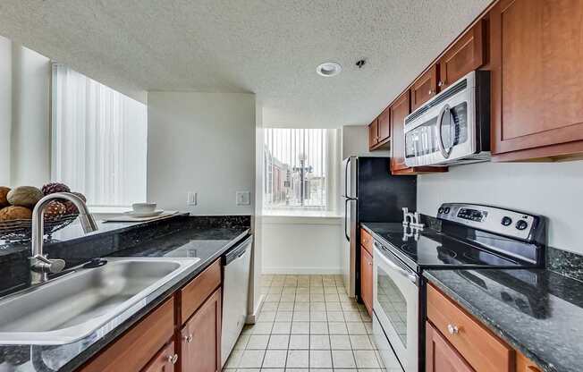 A kitchen with black countertops and white appliances at Lowertown Commons Apartments, St. Paul, 55101
