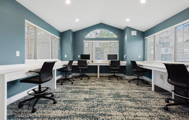 A room with blue walls and a carpeted floor with a desk and chairs.