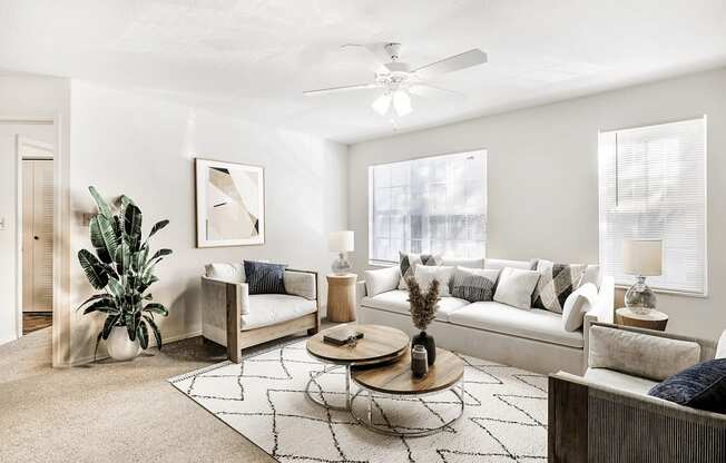 Virtually staged living room with couch, tv, ceiling fan, large windows, and coffee table