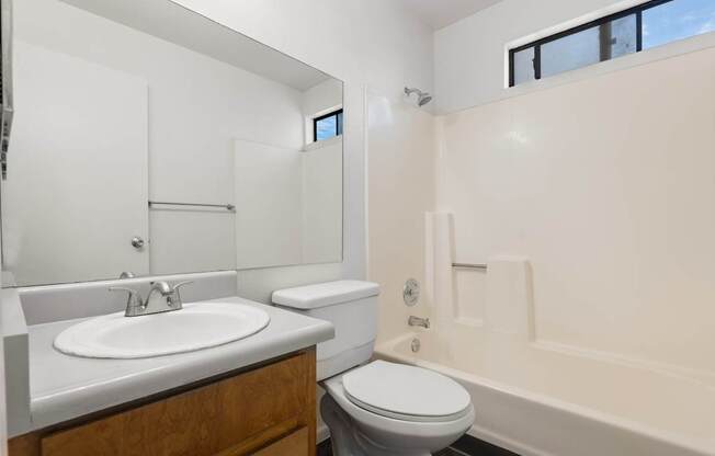 A white bathroom with a toilet, sink, and bathtub.