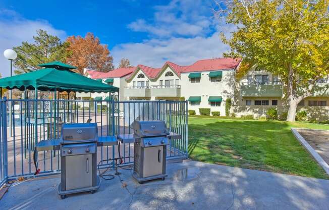 Outdoor BBQ Picnic Area with Grills, Gate, Grass and View of Pool