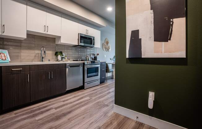 Apartments For Rent In South Park, Los Angeles CA - Emerald - A Stylish And Modern Kitchen With Stainless Steel Appliances, White Countertops, White Cabinetry Above, And Dark Wood Cabinetry Below