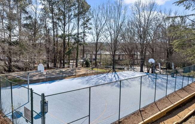 the tennis court is covered in snow and is surrounded by trees