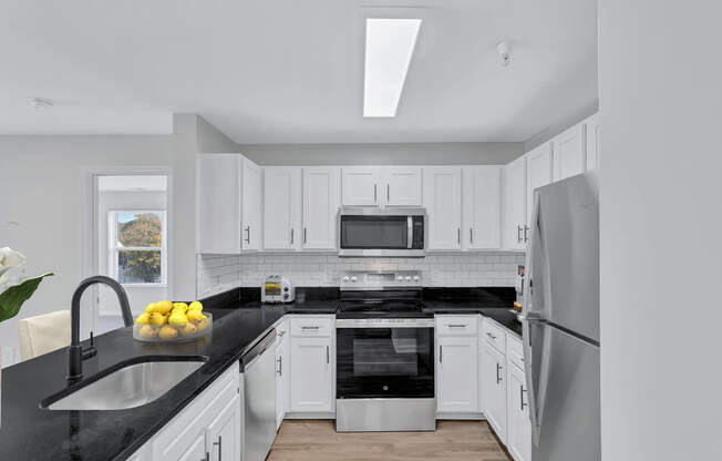 a kitchen with white cabinets and black counter tops