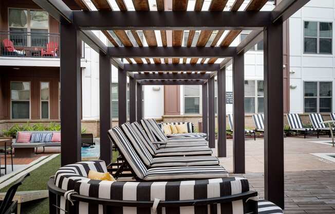 an outdoor lounge area with striped lounge chairs and a pergola