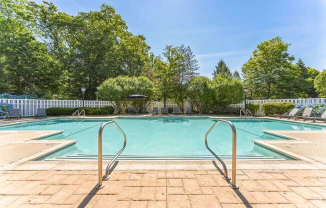 a swimming pool with trees and a white fence around it