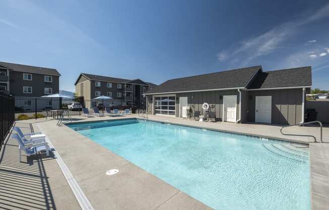 a swimming pool with lounge chairs and umbrellas in front of a building  at Altitude, East Wenatchee