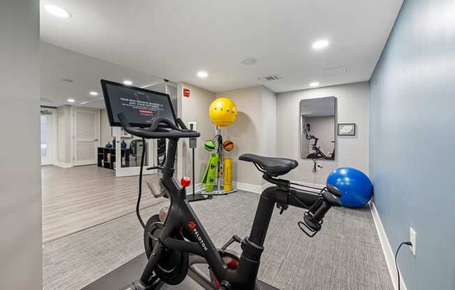 a gym with exercise bikes and a yellow ball on the wall