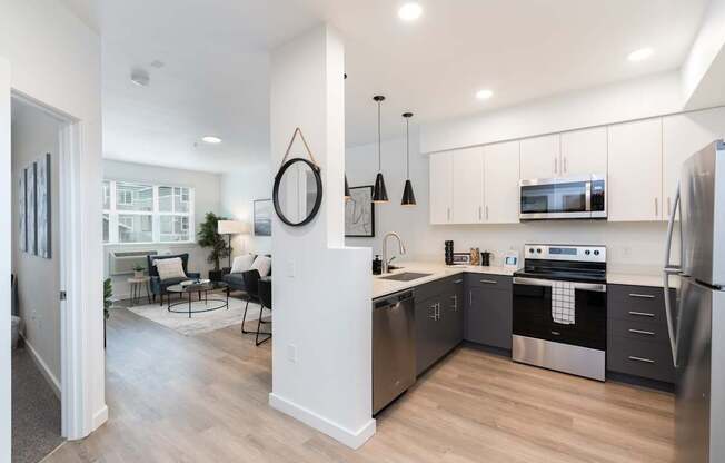 A modern kitchen with stainless steel appliances and a dining area with chairs and a table.
