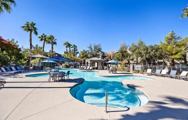 A large swimming pool surrounded by palm trees and lounge chairs.
