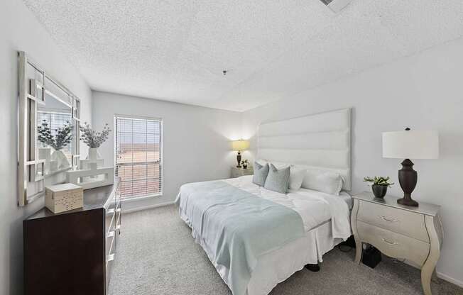 A bedroom with a bed, nightstand, and a window with blinds.