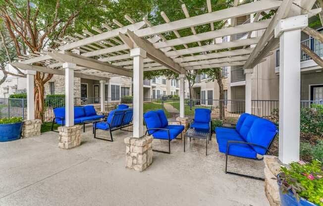a covered patio with blue chairs and a white pergola