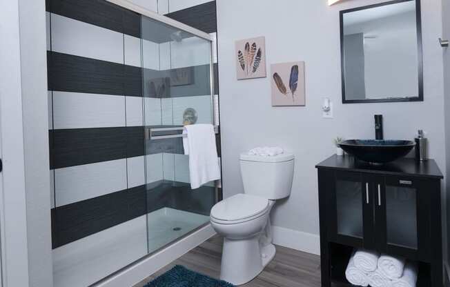 Fusion Las Vegas apartment bathroom with basin sink and black and modern black and white tiled shower with sliding glass door.