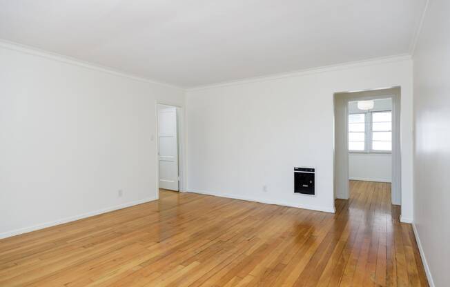 a living room with white walls and a hard wood floor