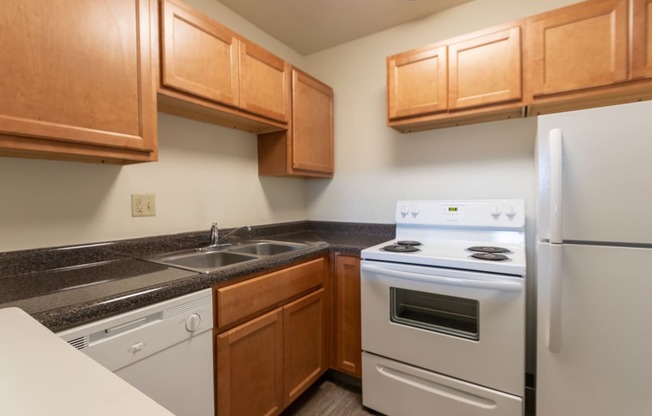 This is a photo of a kitchen with honey oak cabinets and white appliances in a 560 square foot 1, 1 bath apartment at Park Lane Apartments in Cincinnati, OH.
