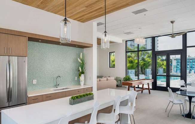 A modern kitchen with a white countertop and white chairs.