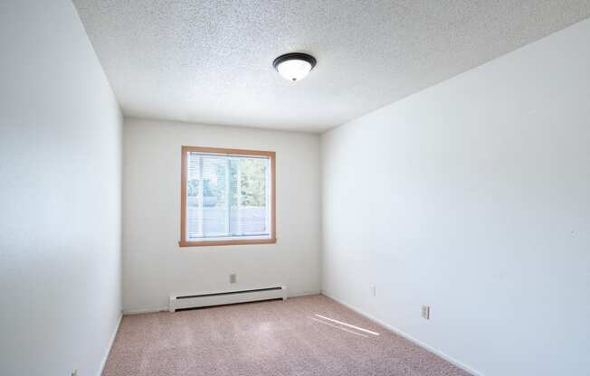 an empty room with white walls and a window. Fargo, ND Betty Ann Apartments