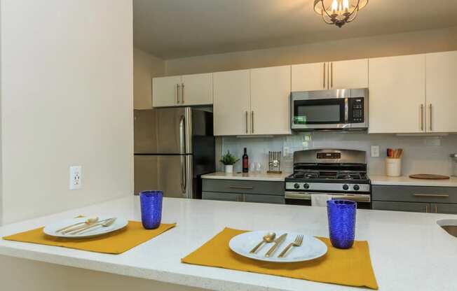 a kitchen with white cabinets and a white counter top with yellow place mats and purple vases