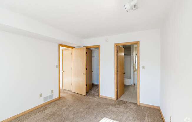A room with a carpeted floor and two open doors.