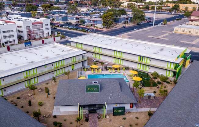 Aerial view of Las Vegas fusion apartments with bright green doors around clubhouse and community pool in desert landscape