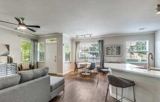 A living room with a grey couch and a bar area.