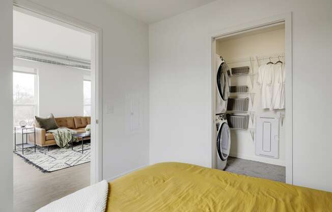 a bedroom with a bed and a closet with a washer and dryer