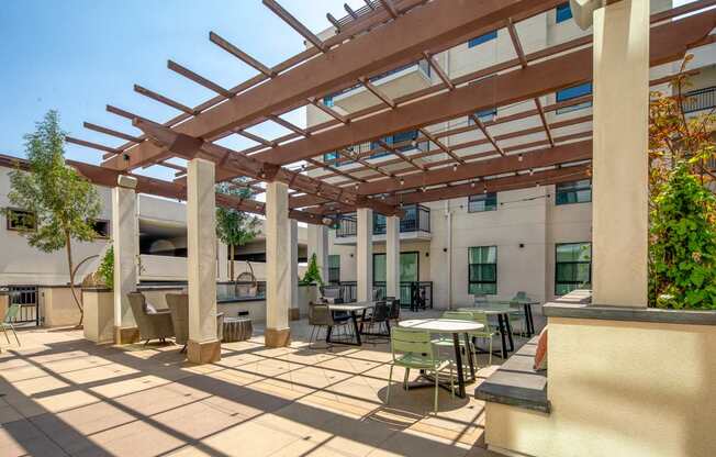 A patio with tables and chairs under a wooden pergola.