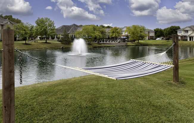 a hammock in front of a lake with a fountain