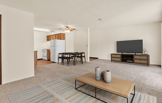 A living room with a television, a dining table, and a refrigerator.
