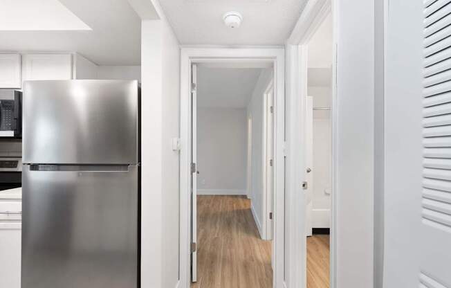 A long hallway with a refrigerator on the left.