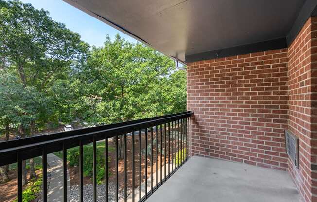 A balcony with a black railing and a brick wall.