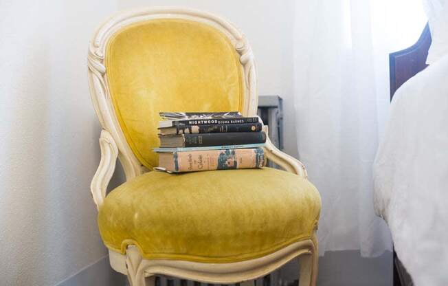 a yellow chair with a pile of books on it at MILEPOST 5 Apartments, PORTLAND