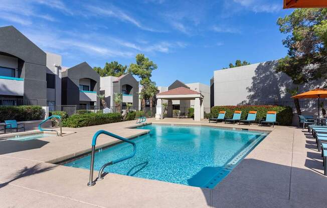 A swimming pool surrounded by lounge chairs and buildings.