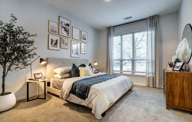 a bedroom with a large window and framed pictures on the wall