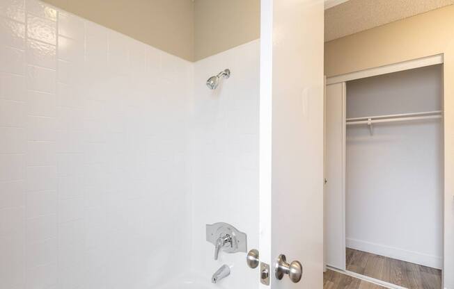 A white door with a silver handle and a silver shower head.