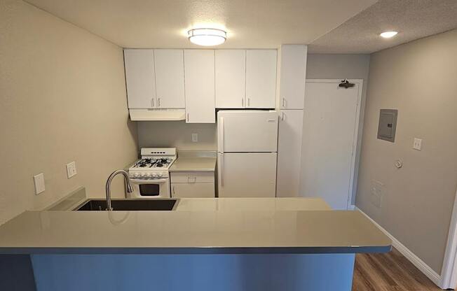A kitchen with white cabinets and a grey counter top.