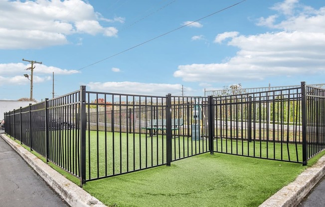 A black metal fence encloses a green lawn.