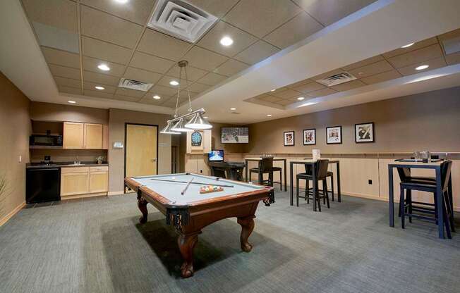 A room with a pool table, a dartboard, and tables.