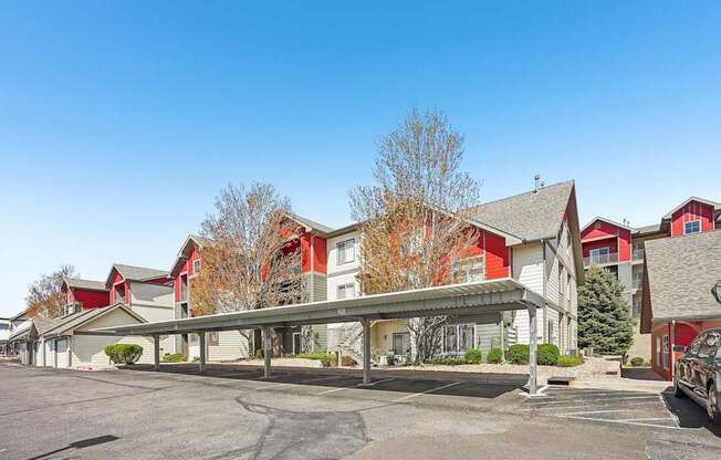 A parking lot in front of a building with a red and white building in the background.