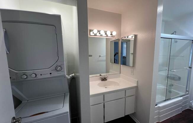 A white bathroom with a washer and dryer built in.