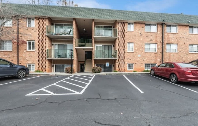 A parking lot in front of a brick apartment building.